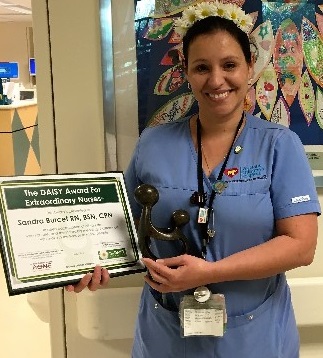 awardee wearing a headband of daisies, daisy award statue, and certificate.