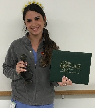 awardee wearing a headband of daisies, daisy award statue, and certificate.