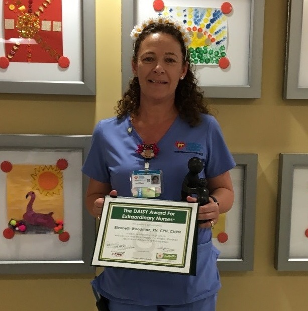 awardee wearing a headband of daisies, daisy award statue, and certificate.