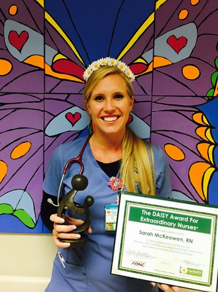 awardee wearing a headband of daisies, daisy award statue, and certificate.