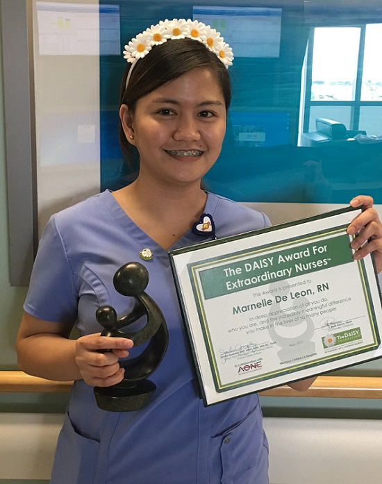 awardee wearing a headband of daisies, daisy award statue, and certificate.