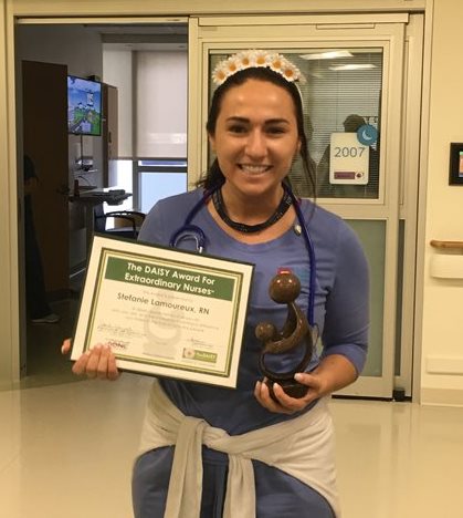 awardee wearing a headband of daisies, daisy award statue, and certificate.