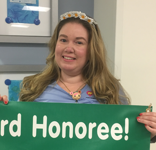 awardee wearing a headband of daisies, daisy award statue, and certificate.