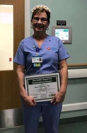 awardee wearing a headband of daisies, daisy award statue, and certificate.