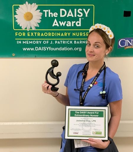 awardee wearing a headband of daisies, daisy award statue, and certificate.