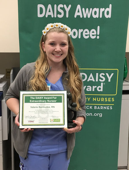 awardee wearing a headband of daisies, daisy award statue, and certificate.