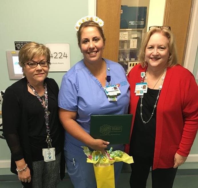 awardee wearing a headband of daisies, daisy award statue, and certificate.