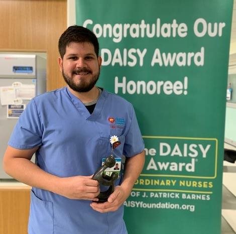 awardee wearing a headband of daisies, daisy award statue, and certificate.