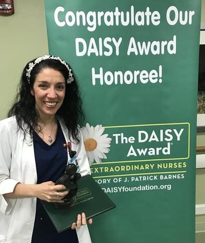 awardee wearing a headband of daisies, daisy award statue, and certificate.