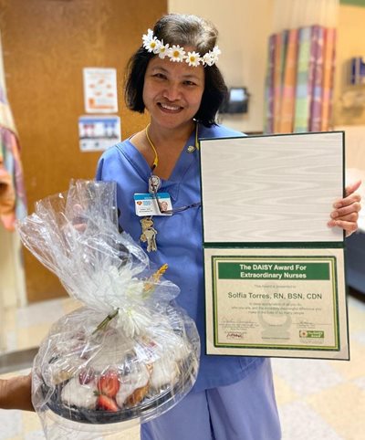 awardee wearing a headband of daisies, daisy award statue, and certificate.