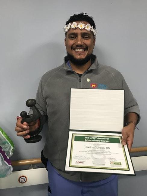 awardee wearing a headband of daisies, daisy award statue, and certificate.