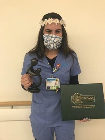 awardee wearing a headband of daisies, daisy award statue, and certificate.