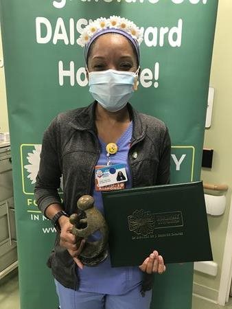 awardee wearing a headband of daisies, daisy award statue, and certificate.