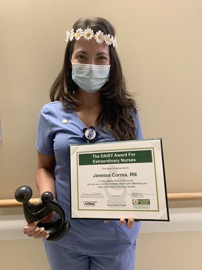 awardee wearing a headband of daisies, daisy award statue, and certificate.