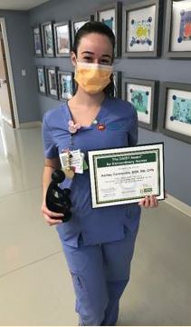 awardee wearing a headband of daisies, daisy award statue, and certificate.