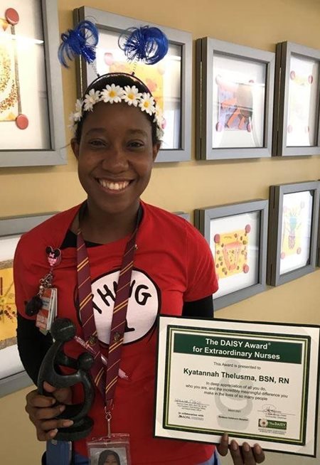 awardee wearing a headband of daisies, daisy award statue, and certificate.