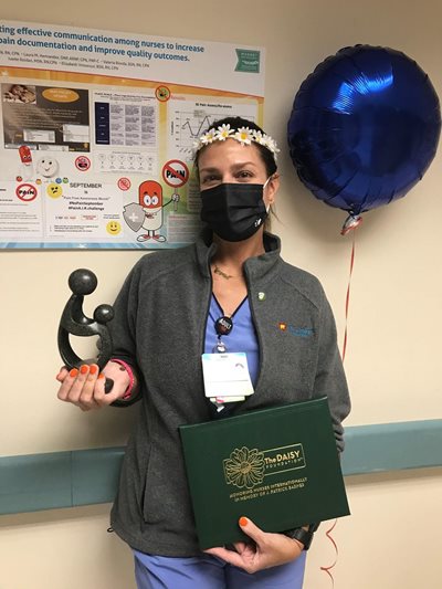 awardee wearing a headband of daisies, daisy award statue, and certificate.