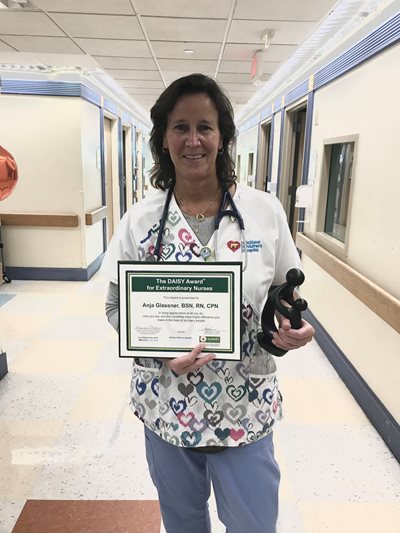 awardee wearing a headband of daisies, daisy award statue, and certificate.