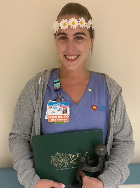 awardee wearing a headband of daisies, daisy award statue, and certificate.