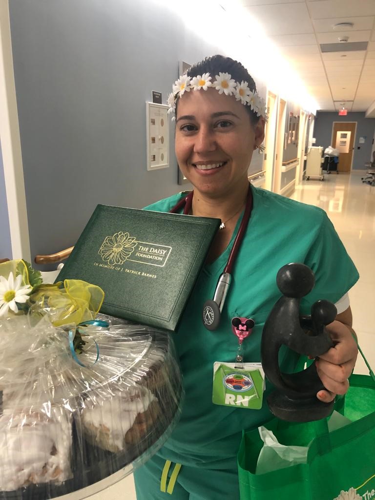 awardee wearing a headband of daisies, daisy award statue, and certificate.