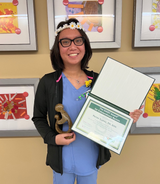 awardee wearing a headband of daisies, daisy award statue, and certificate.