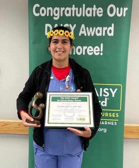 awardee wearing a headband of daisies, daisy award statue, and certificate.