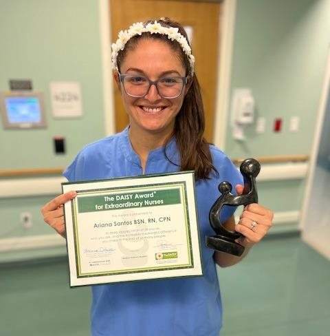 awardee wearing a headband of daisies, daisy award statue, and certificate.