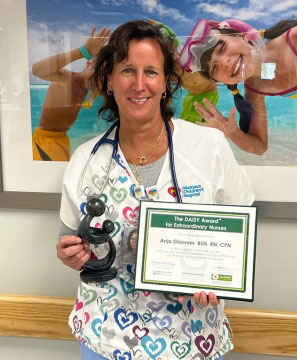 awardee wearing a headband of daisies, daisy award statue, and certificate.