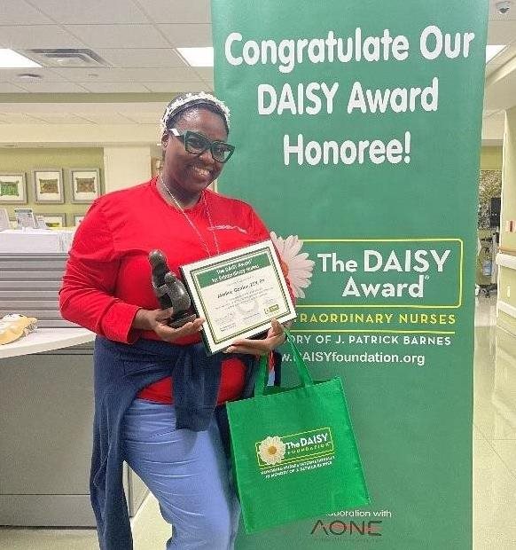 awardee wearing a headband of daisies, daisy award statue, and certificate.