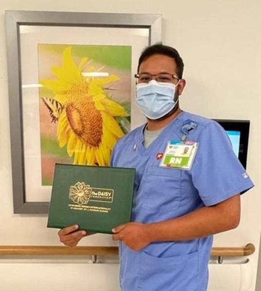 awardee wearing a headband of daisies, daisy award statue, and certificate.