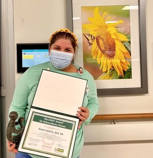 awardee wearing a headband of daisies, daisy award statue, and certificate.