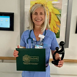 awardee wearing a headband of daisies, daisy award statue, and certificate.