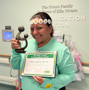 awardee wearing a headband of daisies, daisy award statue, and certificate.