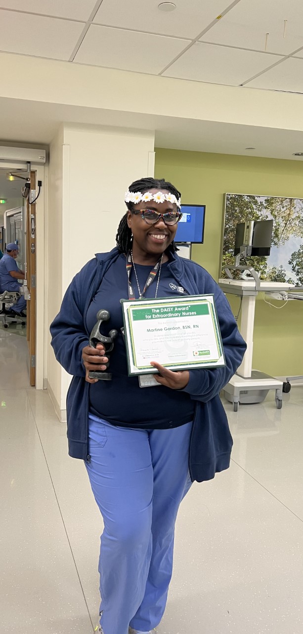 awardee wearing a headband of daisies, daisy award statue, and certificate.