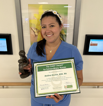 awardee wearing a headband of daisies, daisy award statue, and certificate.