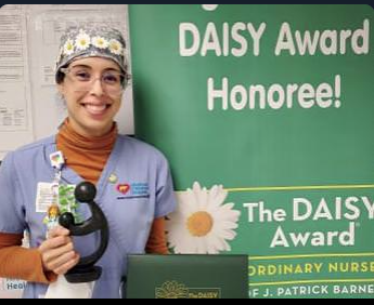 awardee wearing a headband of daisies, daisy award statue, and certificate.