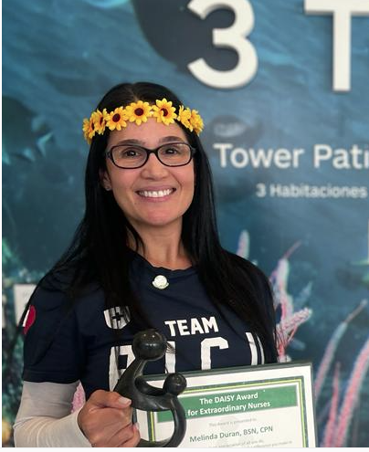 awardee wearing a headband of daisies, daisy award statue, and certificate.