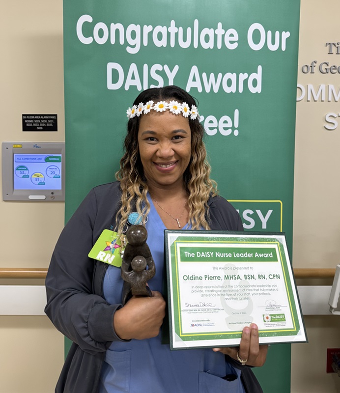 awardee wearing a headband of daisies, daisy award statue, and certificate.