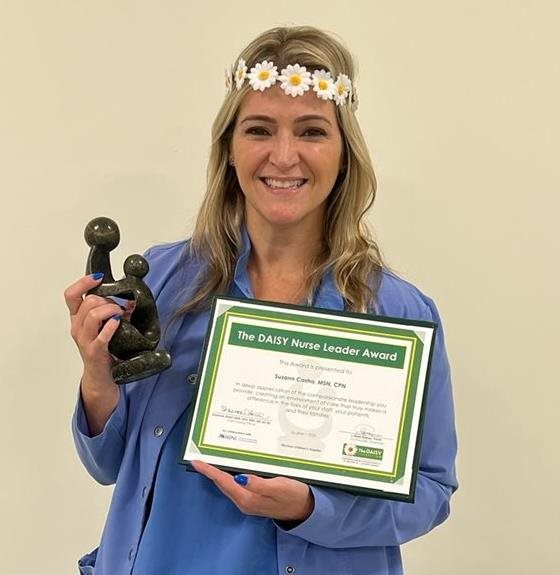 awardee wearing a headband of daisies, daisy award statue, and certificate.