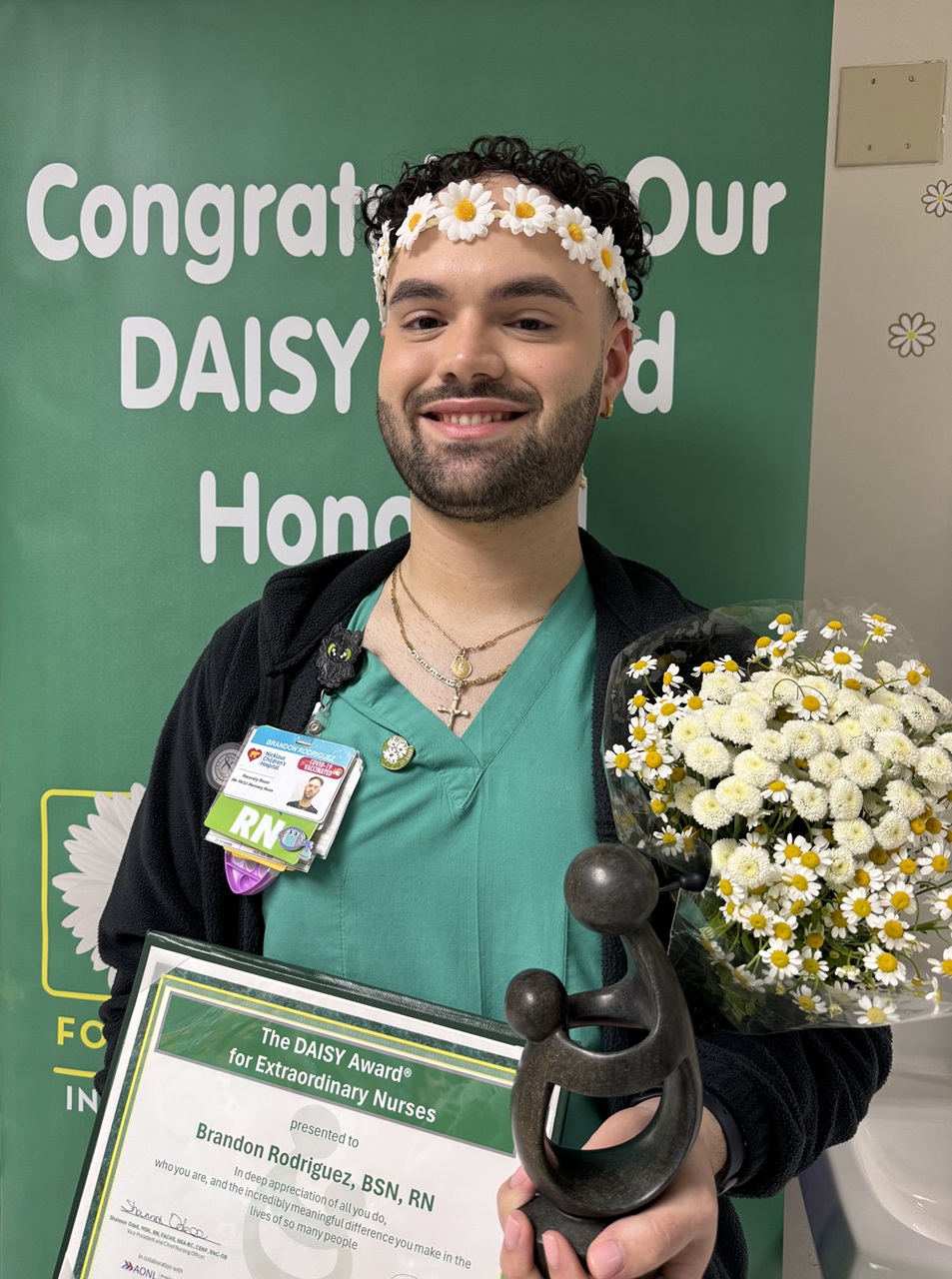 awardee wearing a headband of daisies, daisy award statue, and certificate.