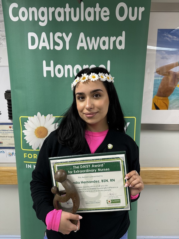 awardee wearing a headband of daisies, daisy award statue, and certificate.