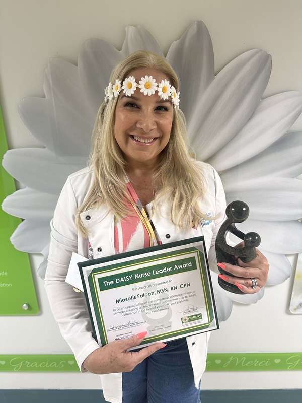 awardee wearing a headband of daisies, daisy award statue, and certificate.