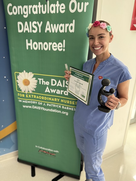 awardee wearing a headband of daisies, daisy award statue, and certificate.