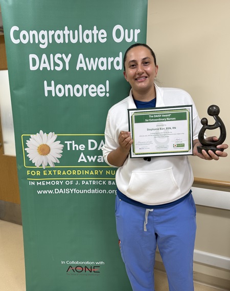 awardee wearing a headband of daisies, daisy award statue, and certificate.