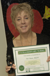 awardee wearing a headband of daisies, daisy award statue, and certificate.