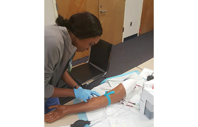 student practing a blood draw on mannequin