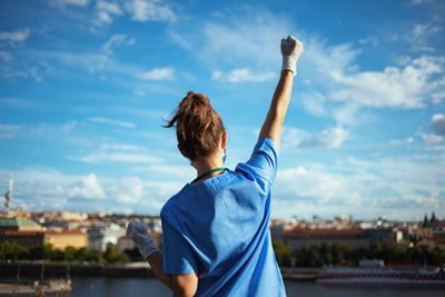 nurse with gloved hand triumphantly throwing fist in the air.