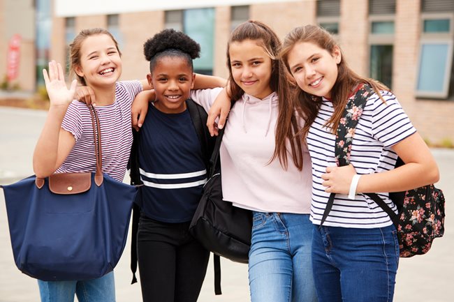 4 middle school aged girls holding bags