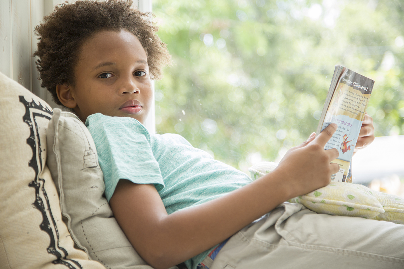 african american boy sitting listlessly by a window