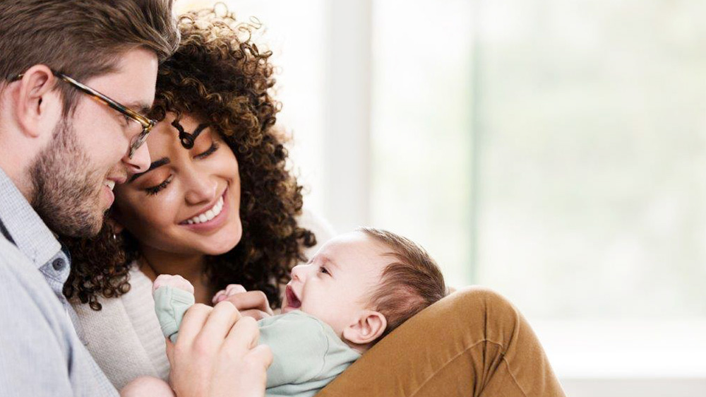 young interracial parents cooing over their baby